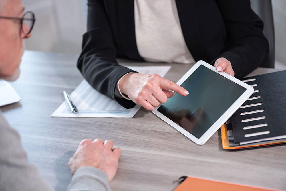 Person zeigt einer anderen etwas auf dem Tablet. Umfeld Arbeit.